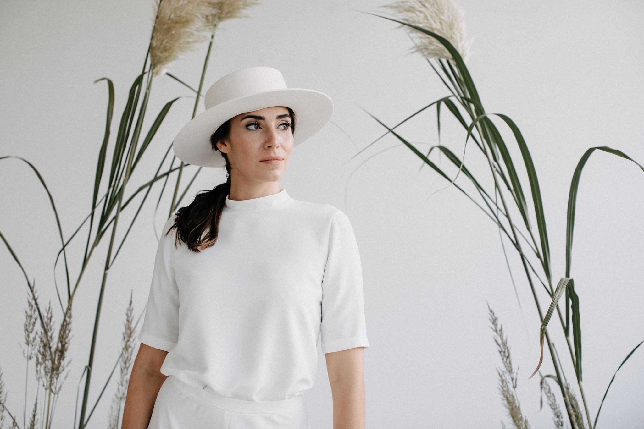 Frau mit weißem Outfit und Hut vor Pampas Gräsern Fotoshooting von Jan Spille Online Goldschmuck kaufen