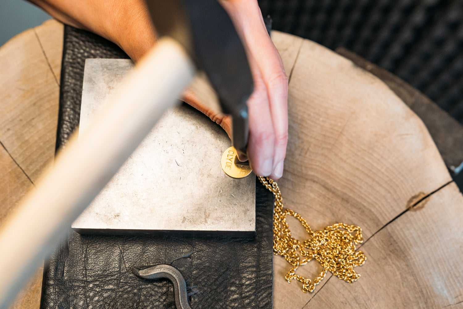 Ein goldener Kettenanhämnger wird in der Goldschmiedewerkstatt gestempelt
