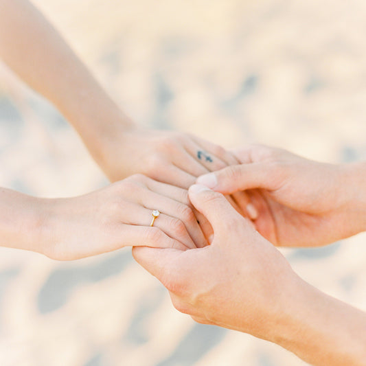 Man und Frau halten Hände zeigen goldenen verlobungsring mit diamant in chatonfassung im jan spille goldschmied online shop