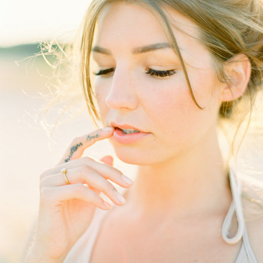 Nahaufnahme einer Frau die ihre Hand ans Gesicht hält und Diamantring mit Krappenfassung aus der Chaton-Kollektion von Jan Spille trägt