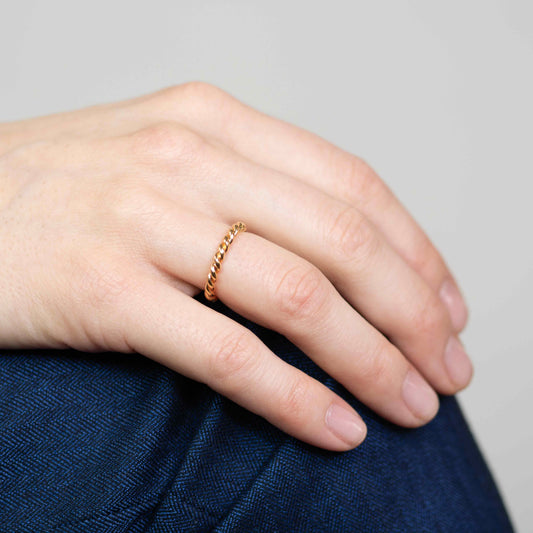 Hand trägt geflochtenen Ring aus Roségold im Kordel-Design