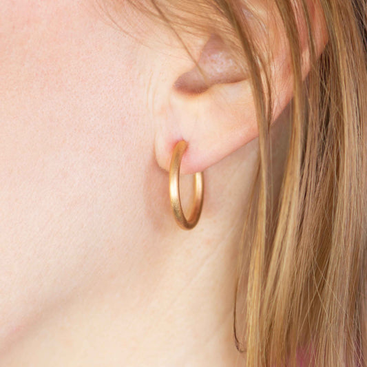 Schlichte Creolen aus Roségold, stilvoll getragen – fair produziert von Jan Spille.