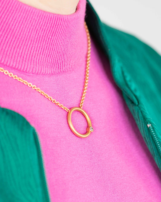 frau mit pinkem pulli trägt Roségold goldkette mit anhänger rund im minimalistischen Design, Rundkollektion von Jan Spille.